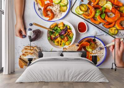 Family eating a healthy vegetarian food. Vegan lunch table top view, plant based diet. Baked vegetables, fresh salad, berries, bread on a white background. Wall mural