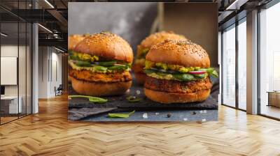 Healthy baked sweet potato burger with whole grain bun, guacamole, vegan mayonnaise and vegetables on a black slate board. Vegetarian food concept, dark background. Wall mural