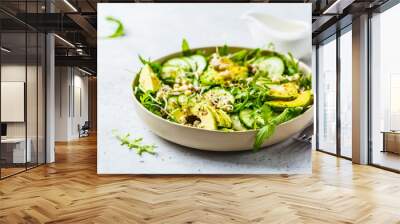 healthy green salad with avocado, cucumber and arugula in white dish. Wall mural