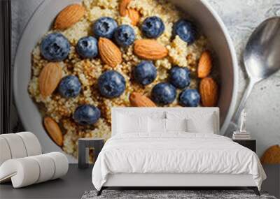 Healthy quinoa porridge with blueberries and almonds with syrup in gray bowl, top view. Vegan food concept. Wall mural