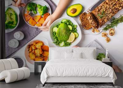 Healthy vegan food lunch, top view. Vegetarian dinner table, people eat healthy food. Salad, sweet potato, vegan cake, vegetables on white background. Wall mural