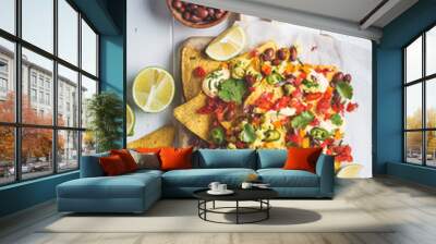 Nachos chips with cheese sauce, guacomole, salsa and vegetables on the board, top view. Party food concept. Wall mural