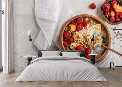 Oatmeal porridge with chia seeds, berries, peanut butter and hemp seeds in wooden bowl, white background. Wall mural