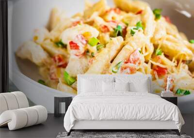 Penne pasta with chicken, pepper and green onions in creamy sauce in a white plate, gray background. Wall mural