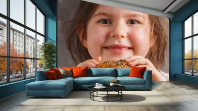 The little girl is eating a healthy baked sweet potato burger with a whole grains bun, guacamole, vegan mayonnaise and vegetables. Child vegan concept, gray background. Wall mural