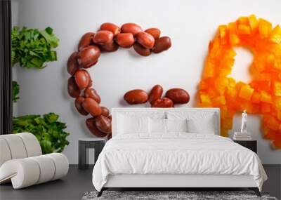 The word vegan on white background, top view. Vegan food concept. Vegan composed of beans, guacamole, vegetables and herbs. Wall mural