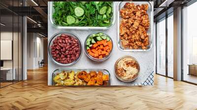 Vegan meal prep containers with  marinated tofu, beans, baked vegetables, green salad and vegetable sticks. Wall mural