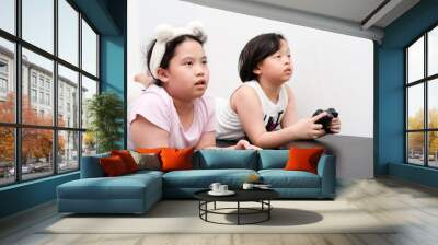 asian children play video game by controller in home Wall mural