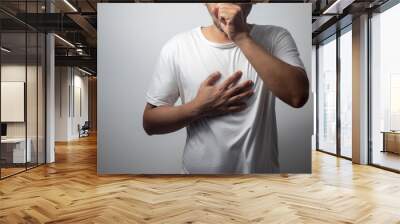 man wearing white shirt coughing on white background Wall mural