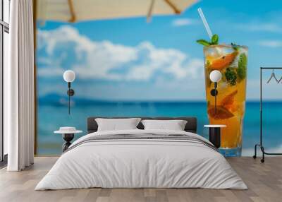 Iced drink with citrus and mint on a beach table under a parasol. Wall mural