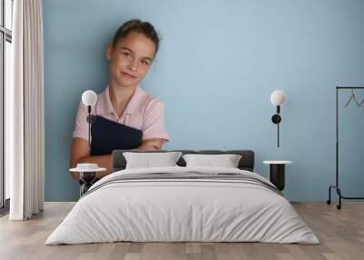 Little emotional teenage girl in pink shirt 11, 12 years old on an isolated blue background with a tablet in her hands.Children's studio portrait. Place the text to copy the place for the inscription Wall mural