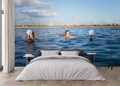 Two girls resting on the dead sea. Two girlfriends swimming in a salt lake. Women with a beautiful figure floating in the water. Wall mural