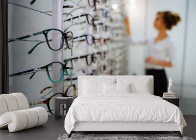 eyeglasses shop. stand with glasses in the store of optics. woman chooses glasses. Wall mural