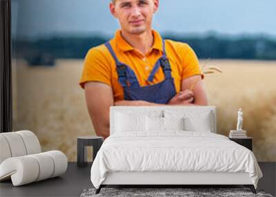 Farmer in field with dry harvest. Gold wheat field on blurred background. Wall mural