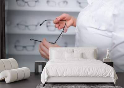 Optician, optometrist, oculist or eye doctor holding glasses and specs with new lenses. Professional eyesight specialist in clinic or shop with spectacles in hand. Bifocal or multifocal eyeglasses Wall mural