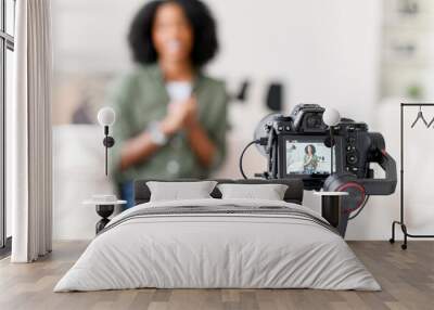 An African-American woman with a radiant smile is seated on a couch, interacting with a camera on a gimbal, creating content in a modern living room with soft natural light, focus on the camera Wall mural