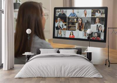 Brainstorm, online video meeting, virtual conference with multi ethnic coworkers, employee, colleagues. View over shoulder of a woman in formal shirt on a screen with webcam shots of diverse people Wall mural