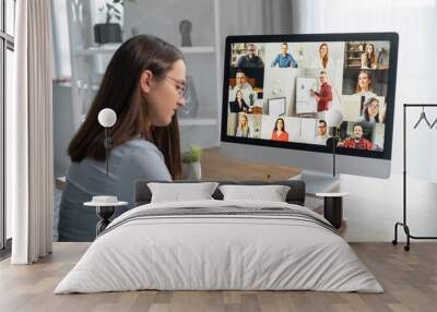 Brainstorm, online video meeting, virtual conference with multi ethnic coworkers, employee, colleagues. View over shoulder of a woman in formal shirt on a screen with webcam shots of diverse people Wall mural