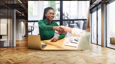 Business women shaking hands in the office during business meeting. Two diverse female entrepreneurs on meeting in boardroom. Female recruiter and employee confirm hiring Wall mural