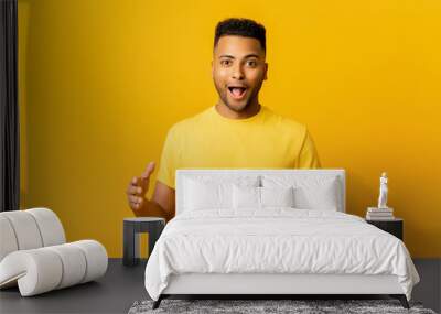 Excited surprised Indian man holding hands in front of him, presenting something, shocked arab guy holding empty space for your product isolated on yellow, demonstrates size. Mockup concept Wall mural