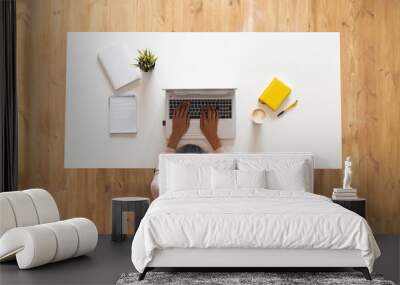 Overhead view of mixed-race ethnic woman or female freelancer with curly hair sitting at the white table desk with well-organized space, typing on the laptop, taking notes, modern home office concept Wall mural