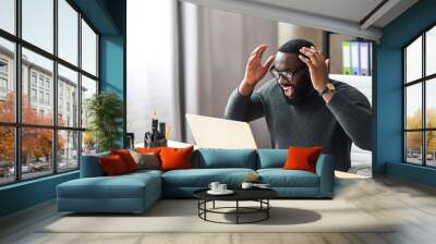 Overjoyed African man raised hands up, a guy in glasses excited and happy with a good news or deal, he looks at laptop screen with triumph Wall mural