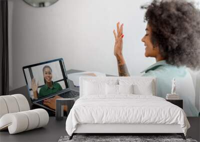 Virtual conference, morning meeting online. Young woman is using app on pc for connection with colleague, employee, she is writing in notebook. Two women have video call together Wall mural