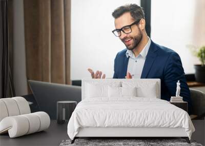 Young bearded businessman entrepreneur in business wear explaining himself, discussing project, gesturing, presenting new business idea to client, team or to investor online on video call via laptop Wall mural