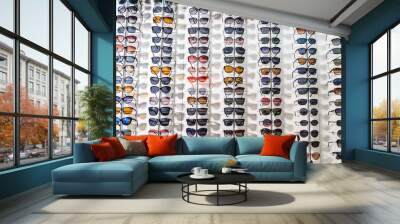 Sunglasses in the shop display shelves. Stand with glasses in the store of optics. Wall mural