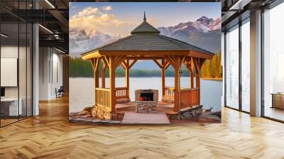 Wooden oak gazebo in a minimalist style with a small fireplace in the center, overlooking the summer lake and mountain peaks visible in the distance; with dense forest at the foot of the mountains Wall mural