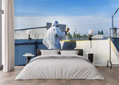 Worker in white suit finishing with paint. Man painting in suit. Wall mural