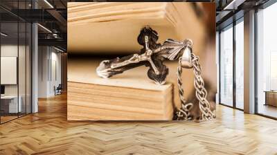 Closeup of Christian cross with silver chain on blank open book with a black wooden background Wall mural