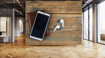 Smartphone, earphone and brown leather wallet on wood table background. Hipster modern life style layout for inserting text Wall mural