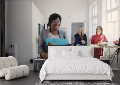 Beautiful young black female manager carrying office box, hired for a new job, multiethnic colleagues welcome and smile. Wall mural