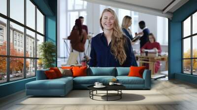 Medium shot portrait of happy positive young blonde business woman smiling at camera at modern loft office workplace. Wall mural