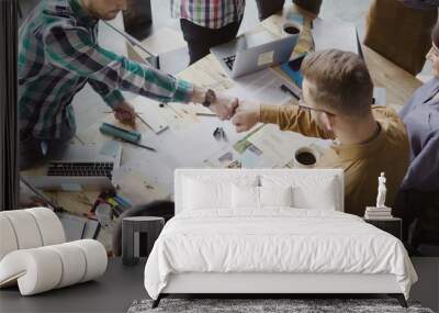 Top view of young business team working together near the table, brainstorming. Two mans fist greeting each other. Wall mural