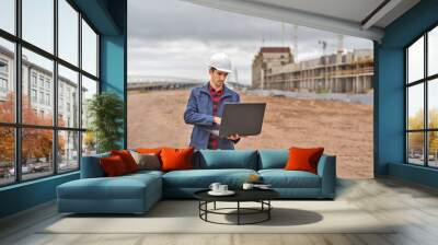 civil engineer in a white helmet looking documents on the background of construction Wall mural