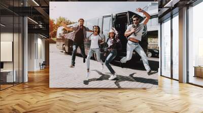 Excited Young People Jumping in front of Tour Bus Wall mural