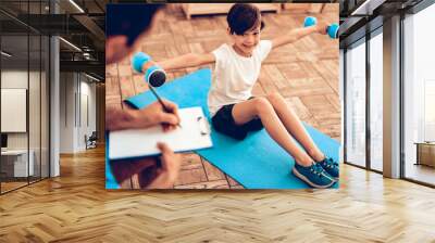 Male Trainer and Boy with Dumbbells Sits on Floor. Wall mural