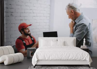 Old Man Giving Broken laptop to Worker in Workshop Wall mural