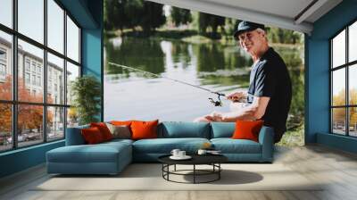 Old Man with Gray Hair Fishing on River in Summer. Wall mural