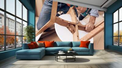 The man handyman is engaged in assembling the chair. The repairman is engaged in mending chair. Wall mural