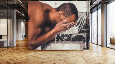 Young Afro-American Man Washing Face in Bathroom. Wall mural