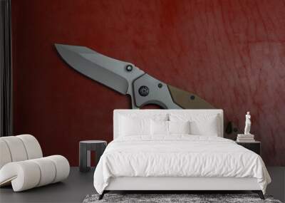 An unfolded tactical military knife with a sharp blade. Tool against the natural leather. Wall mural