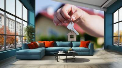 Man holds the keys to the house in his hands against the backdrop of residential buildings. Concept for buying and renting apartments. Wall mural