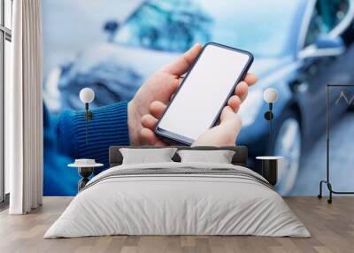 Mock-up of a smartphone in the hands of a man against the background of a car. Wall mural