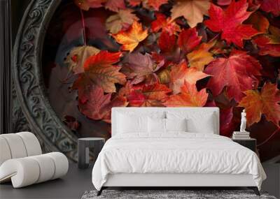 A close-up view of an ornate, dark pot filled with colorful autumn leaves. The leaves are predominantly shades of red and orange, and they float in a shallow pool of water. The pot's intricate design  Wall mural