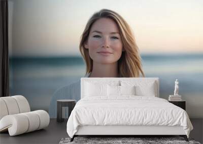 A serene woman smiles softly while standing on a beach during twilight, with gentle waves crashing in the background Wall mural