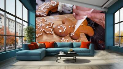 Christmas bakery. Decorating homemade gingerbread man with icing, close up. Festive culinary and New Year traditions concept Wall mural