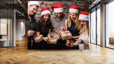 Christmas party, New Year celebration, sale, black friday, holiday, fun, togetherness. Group of happy smiling people in Santa caps opening gift boxes Wall mural